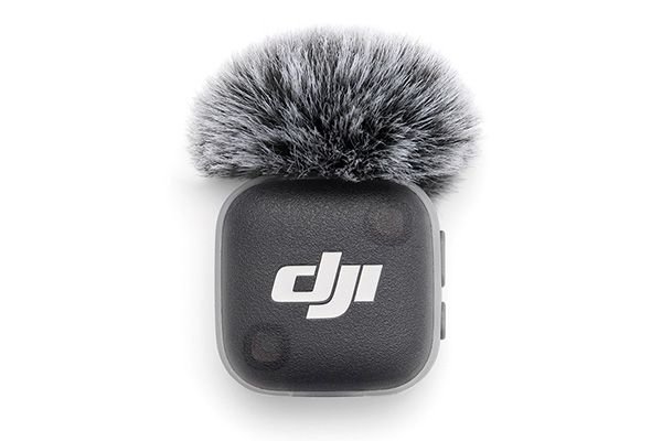 DJI wireless microphone transmitter with a fluffy windscreen (deadcat) attached for wind noise reduction.